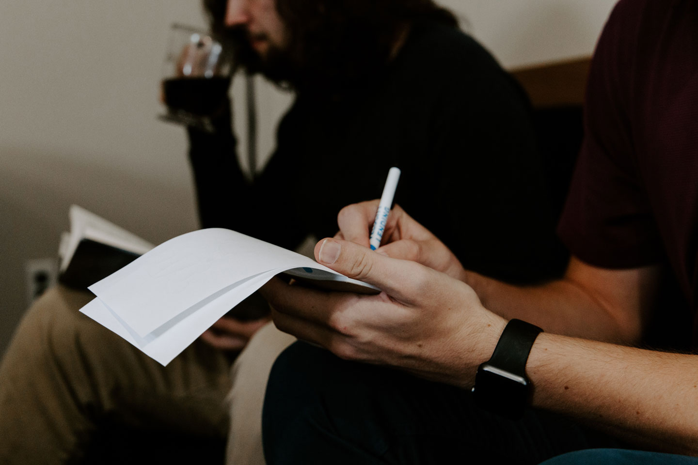 Person writing on a note pad with a pen